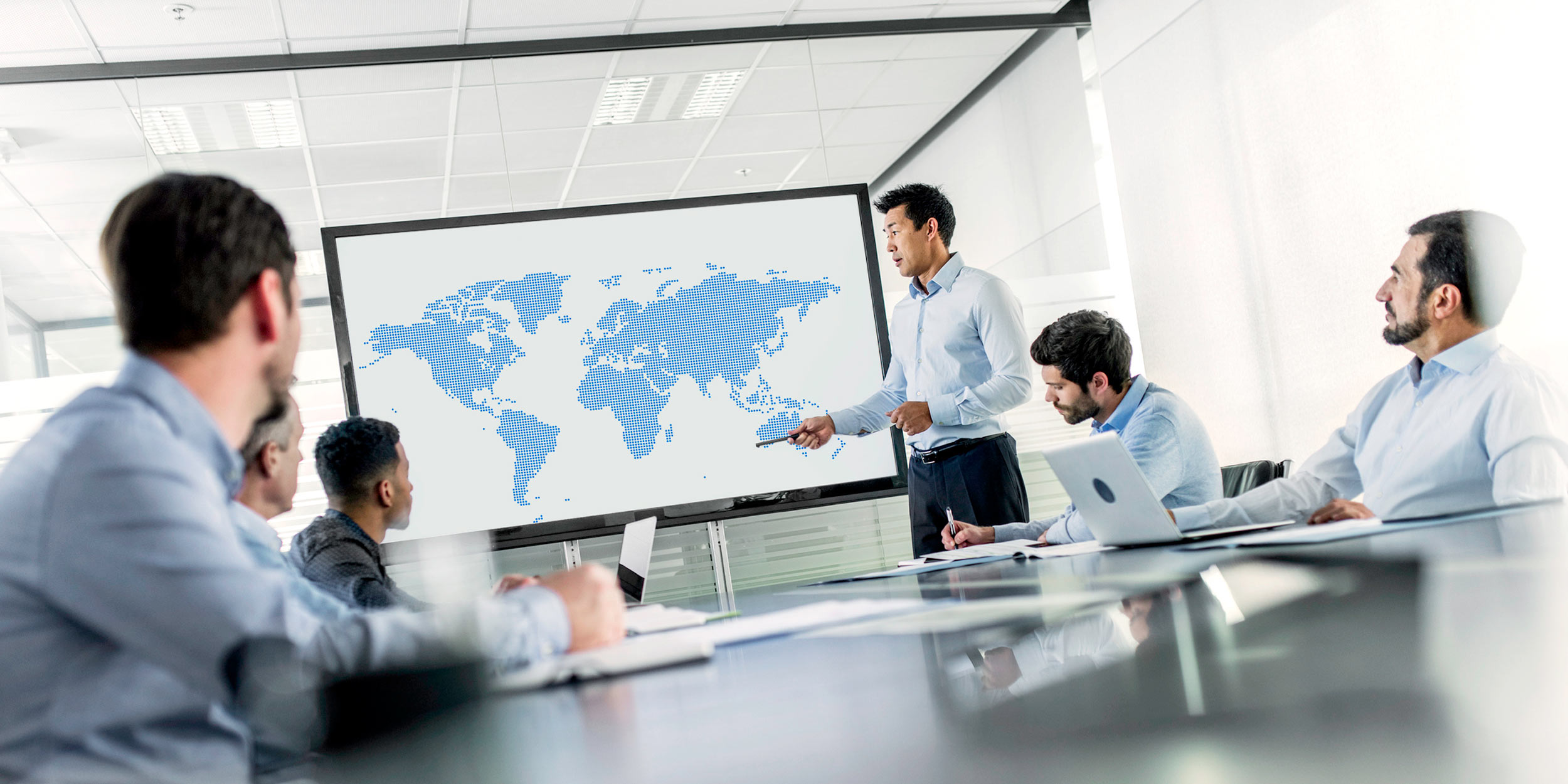 Image of colleagues in a meeting room with world map