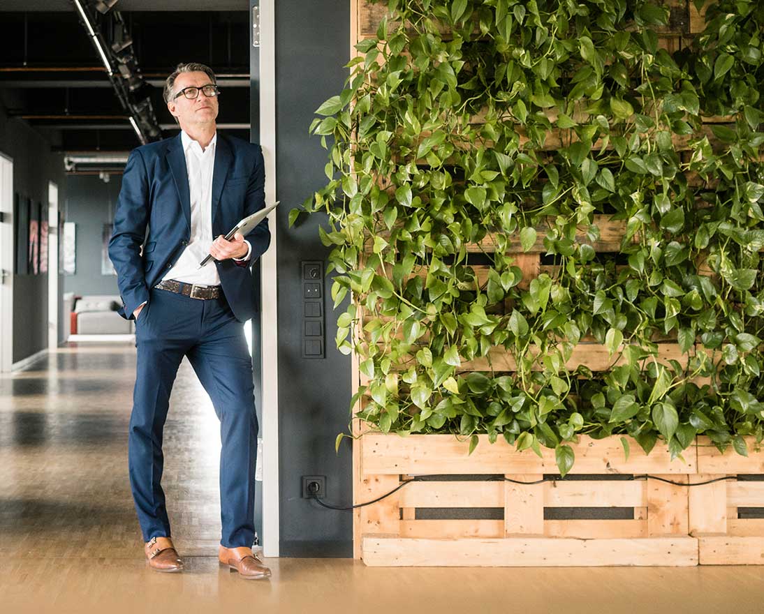 man standing next to wall with plants