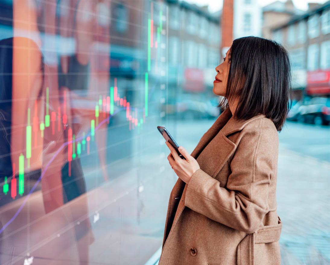 Woman looking at stock market screen while holding phone