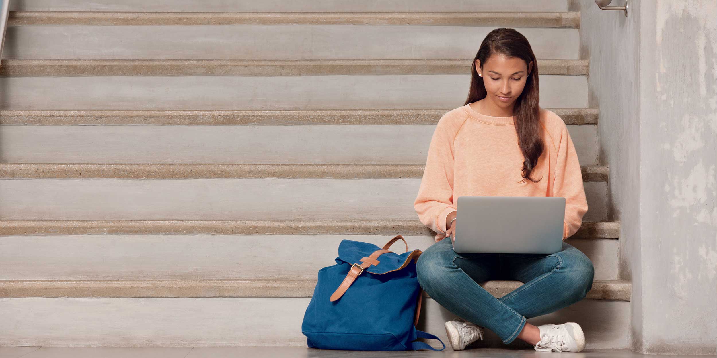 Woman working on laptop sitting on stairs
